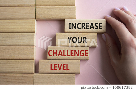 Challenge Level symbol. Concept word Increase your Challenge Level on wooden blocks. Beautiful pink background. Businessman hand. Business and Increase your Challenge Level concept. Copy space Challenge Level symbol. Concept word Increase your Challenge Level on wooden blocks. Beautiful pink background. Businessman hand. Business and Increase your Challenge Level concept. Copy space 108617392