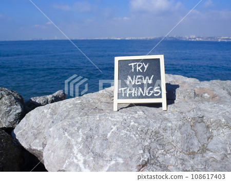 Try new Things symbol. Concept words Try new Things on black chalk blackboard blocks. Beautiful sea green background. Business and Try new Things concept. Copy space. 108617403