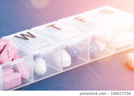 Capsule in the pill box on the blue background. Pill dispenser. 108617556