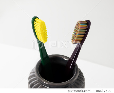 Toothbrushes in ceramic bowl on blurred background. Colorful toothbrushes, healthy tooth concept. 108617590