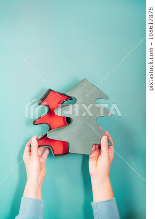 Top view female hands holding open empty Christmas gift box in the shape of Christmas trees on the turquoise background. Craft gift box packaging ideas. Christmas presents delivery service. Vertical. Top view female hands holding open empty Christmas gift box in the shape of Christmas trees on the turquoise background. Craft gift box packaging ideas. Christmas presents delivery service. Vertical. 108617878