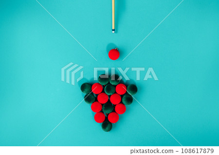 Creative Christmas tree made from red and green velvet Christmas balls and billiard cue on a turquoise background like pool table. Minimal Christmas or New Year concept. top view, copy space Creative Christmas tree made from red and green velvet Christmas balls and billiard cue on a turquoise background like pool table. Minimal Christmas or New Year concept. top view, copy space 108617879