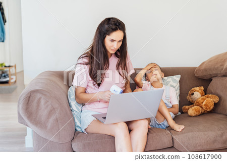 Stressed mother talking with pediatrician doctor during online video chat on laptop, worried about her son's health, checking child's temperature. Telemedicine, telehealth. Flu and cold season. 108617900