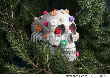 skull covered with multiple plastic flowers in different colors 108618442