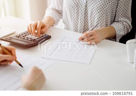 Two accountants using a calculator and laptop computer for counting taxes at white desk in office. Teamwork in business audit and finance 108618791