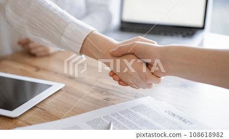 Business people shaking hands above contract papers just signed on the wooden table, close up. Lawyers at meeting. Teamwork, partnership, success concept 108618982