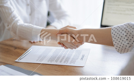 Business people shaking hands above contract papers just signed on the wooden table, close up. Lawyers at meeting. Teamwork, partnership, success concept 108619015