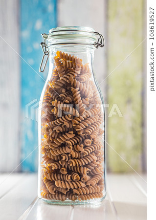 Raw whole grain fusilli pasta. Uncooked pasta in jar. Raw whole grain fusilli pasta. Uncooked pasta in jar. 108619527