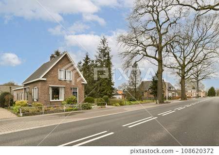 a street with houses and trees in the middle part of the photo is taken on a sunny, clear day a street with houses and trees in the middle part of the photo is taken on a sunny, clear day 108620372