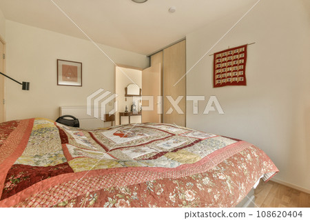 a bed with quilts on it in a room that has white walls and wood flooring around the headboard 108620404