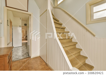 a staircase leading up to the second floor in a new home with wood floors and white panelling on the walls 108620421