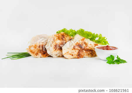 Chicken fillets fried until half cooked, semi-finished product with fresh herbs on a white background. Fast food. Quick cooking at home. Copy space.Fast cooking.Fast homemade food. 108621561