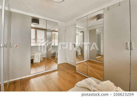 a modern bathroom with wood flooring and large mirrors on the wall in front of the bathtub is reflected in the mirror a modern bathroom with wood flooring and large mirrors on the wall in front of the bathtub is reflected in the mirror 108623204