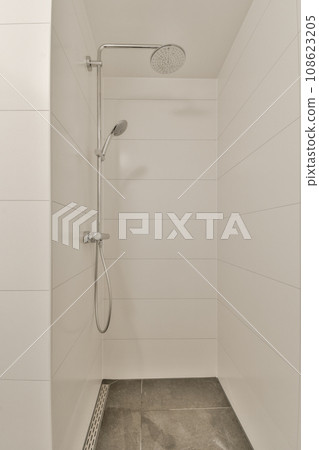 a walk in shower with tile flooring and white tiles on the wall behind it is an open shower head a walk in shower with tile flooring and white tiles on the wall behind it is an open shower head 108623205