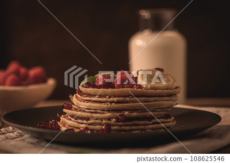 Pancakes with raspberries, banana slices, pomegranate seeds and honey 108625546