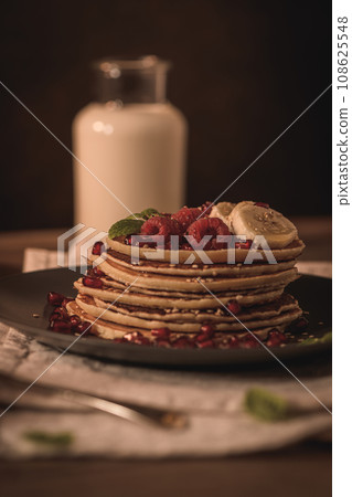 Pancakes with raspberries, banana slices, pomegranate seeds and honey Pancakes with raspberries, banana slices, pomegranate seeds and honey 108625548