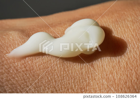 A smear of white moisturizer or sunscreen on a woman's hand. 108626364