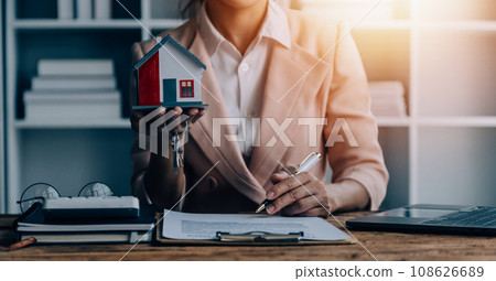 Real estate broker agent presenting and consult to customer to decision making sign insurance form agreement, buy and sell home model, concerning mortgage loan offer for and house insurance 108626689