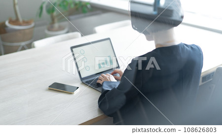 A woman working on a computer through the window A woman working on a computer through the window 108626803