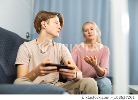 Teenager with smartphone not paying attention to mother talking to him 108627201