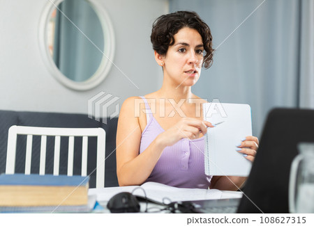 Female student studying at home using laptop and internet 108627315