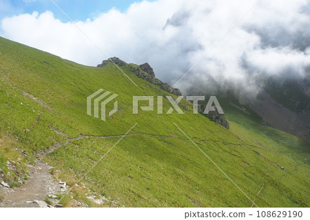 A gentle green mountain trail and fog ahead in France 108629190
