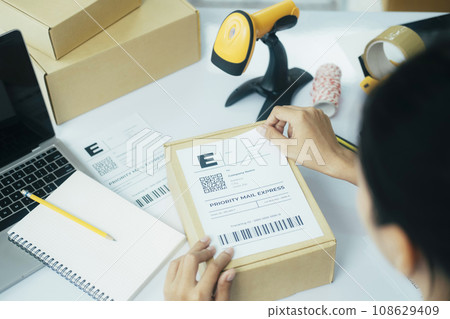 Young business owner putting shipping label on parcel.. Young business owner putting shipping label on parcel.. 108629409