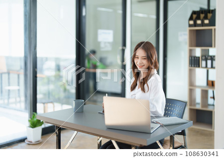 Portrait of a beautiful Asian teenage girl using computer for video conferencing at office. 108630341