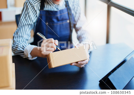 Starting small business entrepreneur of independent Asian female online seller packing products to send to customers and SME delivery concept. Starting small business entrepreneur of independent Asian female online seller packing products to send to customers and SME delivery concept. 108630345