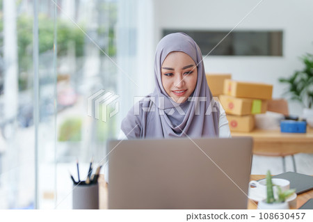 Beautiful Muslim woman using computer to check customer orders, small business owners or sme concepts. Beautiful Muslim woman using computer to check customer orders, small business owners or sme concepts. 108630457