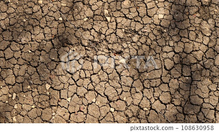 barren dry soil with cracked crust as a natural background on the theme of climate change and drought in agriculture, graphic texture of dried out earth in cracks in sunlight 108630958