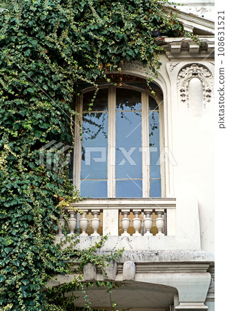 Beautiful French windows. Window frames with wooden shutters. Windows of a private house with flower pots and wooden shutters, Nice, France Beautiful French windows. Window frames with wooden shutters. Windows of a private house with flower pots and wooden shutters, Nice, France 108631521