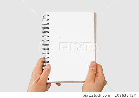 Female Hand Holding Notepad with Blank Page Isolated On Gray Neutral Studio Background. Close Up. Chroma Key Screen. Woman's Hand with Empty Card Paper MockUp. Advertisement gesture. Notebook Mock Up. 108632437