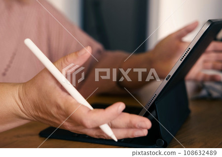Unrecognizable Woman hand using a graphic tablet computer with stylus pencil pen in a cafe. Cropped shot of female working on a digital touchscreen device in remote workplace. Corporate technology 108632489