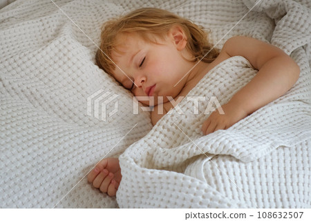 Peaceful adorable baby sleeping on a bed at home. Slumbering little child. Two years old girl sleeps peaceful at domestic room interior background. Serene dream. Cute face close up. Deep kid slumber Peaceful adorable baby sleeping on a bed at home. Slumbering little child. Two years old girl sleeps peaceful at domestic room interior background. Serene dream. Cute face close up. Deep kid slumber 108632507