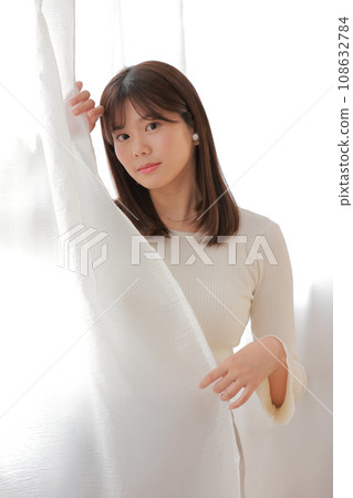 Young woman peeking out from the curtain_1 Young woman peeking out from the curtain_1 108632784