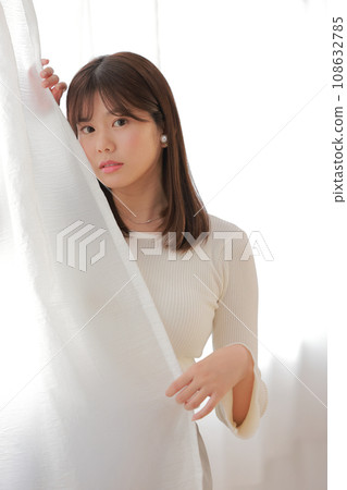 Young woman peeking out from the curtain_Sad expression 1 Young woman peeking out from the curtain_Sad expression 1 108632785