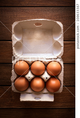 Egg box on a rustic wooden board 108633387