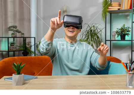 Asian man use virtual reality headset typing virtual keyboard play simulation 3D video game at home Asian man use virtual reality headset typing virtual keyboard play simulation 3D video game at home 108633779