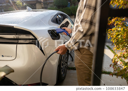 一名男子試圖為插電式混合動力汽車充電 一名男子試圖為插電式混合動力汽車充電 108633847