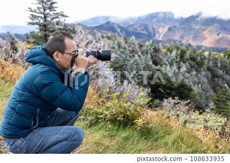 一位中年男子在旅行目的地拍攝志賀高原的秋景。 108633935