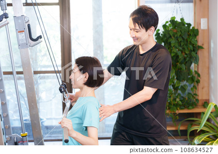 Woman and trainer exercising in the gym Woman and trainer exercising in the gym 108634527