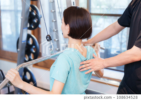 Woman and trainer exercising in the gym 108634528