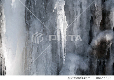 frozen icicles and icing on a stone wall in winter 108635428
