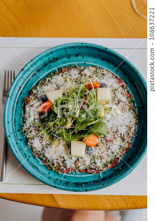 Beef carpaccio with pesto sauce and parmigiano cheese decorated by salad and fruit. Restaurant menu 108637221