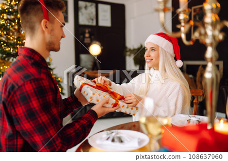 Young couple with Christmas gifts at home near Christmas tree. Romantic day. Holidays. New Years. 108637960