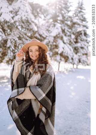 Beautiful woman standing among snowy trees and enjoying first snow. Happy winter time. Christmas. 108638333
