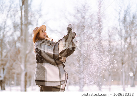 Beautiful woman standing among snowy trees and enjoying first snow. Happy winter time. Christmas. 108638338