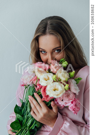 Beautiful woman in pink dress with flowers in the room for a holiday Beautiful woman in pink dress with flowers in the room for a holiday 108638682