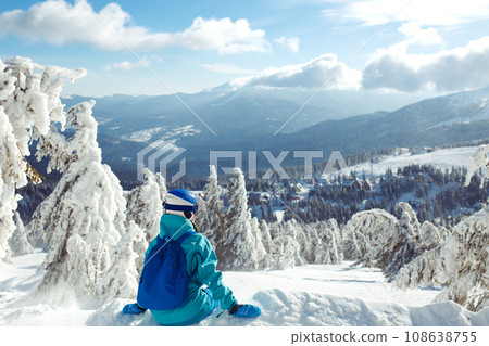 Girl in winter clothes drinking tea on the background of snow-capped mountains on the sunny day. 108638755